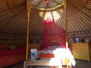 een slaapkamer in een yurt met een bed en een tafel bij Le Bois Faé in La Bastide