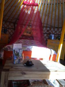 uma mesa numa tenda com uma cama e um candeeiro em Le Bois Faé em La Bastide