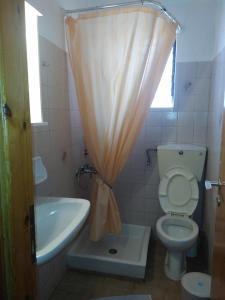 een badkamer met een toilet, een wastafel en een douchegordijn bij Astir Rooms in Póros