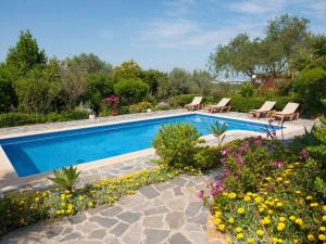 una piscina con sillas y flores en un patio en Belvilla by OYO Can Jurat, en Ses Paisses
