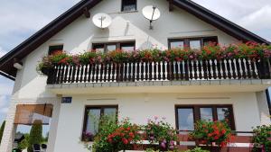 a white house with flowers on a balcony at Guest House Adrijana in Seliste Dreznicko