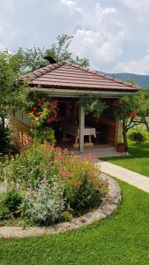 un pabellón con un banco en un jardín con flores en Guest House Adrijana, en Selište Drežničko