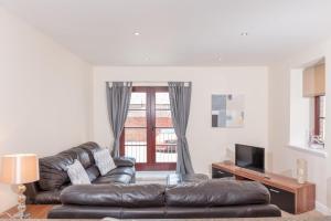 a living room with a leather couch and a television at Elliot Suite No2 - Donnini Apartments in Ayr