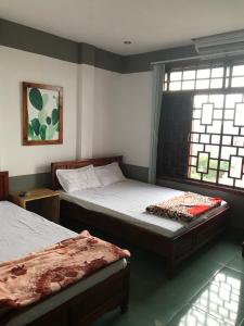 ドンホイにあるThao Trang Hotelのベッドルーム1室(ベッド2台、窓付)