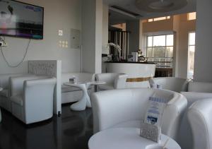a waiting room with white chairs and tables and a tv at Orient House in Hail