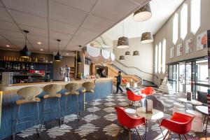 a restaurant with red chairs and a bar at Ibis Château-Thierry in Essômes-sur-Marne