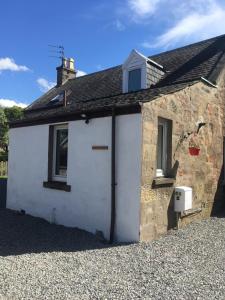 a small white cottage with a window and a roof at Whisky Cottage in Inverness