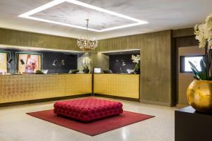 a lobby with a red ottoman in front of a counter at Rosa Grand Milano - Starhotels Collezione in Milan