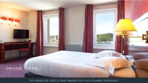um quarto de hotel com uma cama, uma secretária e janelas em Grand Hôtel Bénodet Abbatiale Riviera Bretonne em Bénodet