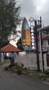 a sign for a restaurant next to a fence at BoraBora Beach Guesthouse Penang in George Town