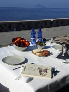 stół z talerzami i miskami owoców i wody w obiekcie NerOssidiana sul mare di Lipari w mieście Lipari