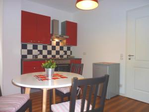 eine Küche mit einem Tisch, Stühlen und roten Schränken in der Unterkunft City Apartment Jena in Jena
