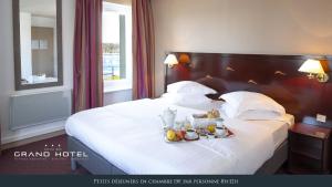 a hotel room with a large bed and a large window at Grand Hôtel Bénodet Abbatiale Riviera Bretonne in Bénodet
