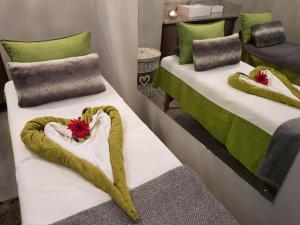 two beds in a room with red flowers on them at Chill Pepper Boutique Hotel in Nelspruit