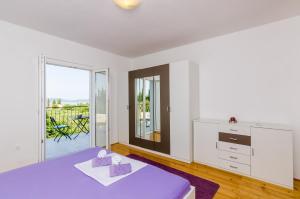 a bedroom with a purple bed and a balcony at Apartment & Rooms Maždin in Banići