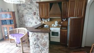 a kitchen with wooden cabinets and a stone wall at Το πετρινο in Agia Marina Mikrolimanou