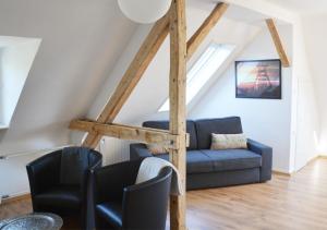 ein Wohnzimmer mit einem blauen Sofa und 2 Stühlen in der Unterkunft Altenbochumer Apartment in Bochum