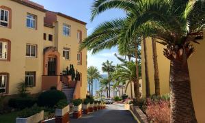 a street in front of a building with palm trees at Macdonald Doña Lola Resort in La Cala de Mijas