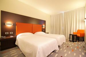 pokój hotelowy z 2 łóżkami i pomarańczowym zagłówkiem w obiekcie Hotel Major w mieście Ronchi dei Legionari +30 zdjęć