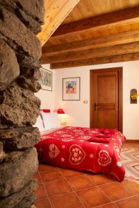 a bedroom with a red bed in a stone wall at La Terrasse d'Ozein in Ozein