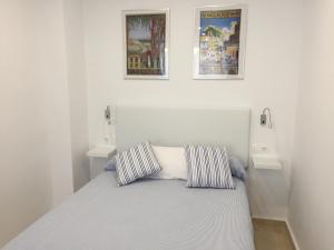 カディスにあるLoft Playa Santa María (Cádiz)の白いベッドルーム1室(ベッド1台付)、壁に2枚の絵画が備わります。