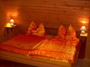 a bed with an orange comforter and two lamps at Ferien auf dem Lande in Leopoldshagen