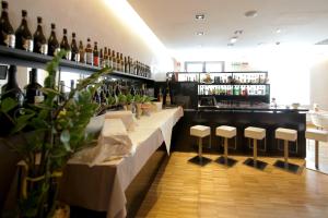 a bar with a row of stools and bottles of wine at Hotel Major in Ronchi dei Legionari