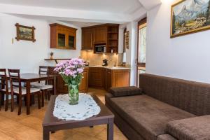 uma sala de estar com um sofá e uma mesa com flores em udanypobyt Apartamenty Pastelowe em Zakopane