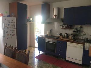 eine Küche mit blauen Schränken und einem weißen Kühlschrank in der Unterkunft Apartments Stevo Nikočević in Bar
