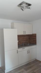 eine Küche mit weißen Schränken und einer Spüle in der Unterkunft Ferienwohnung Gänseblümchen in Wartenburg + 34 Fotos