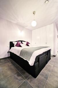 Un dormitorio con una gran cama negra con almohadas moradas en B&B Villa Curtricias, en Kortessem