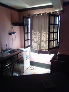 a kitchen with a sink and a window with curtains at Villa Cassis in Ivato