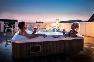 維洛納的住宿－科特昂迦若酒店，两人在热水浴缸中享用一杯葡萄酒