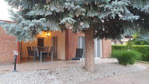 a patio with a table and chairs under a tree at Mimi Apartman in Balatonalmádi