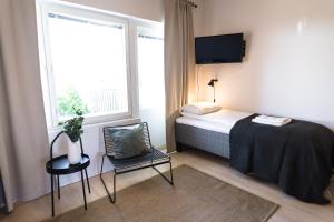 - une chambre avec un lit, une chaise et une fenêtre dans l'établissement Spot Apartments Uusmäki, à Espoo