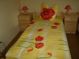 a bed with red flowers on it with two night stands at Gasthof Zum Stausee in Engelskirchen