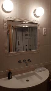 a bathroom with a sink with a mirror and a shower at Mimi Apartman in Balatonalmádi