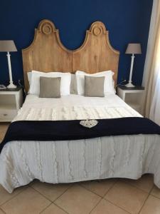 a large bed with a large wooden headboard and pillows at Relais Fenicottero Rosa in Porto San Paolo