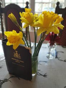 um vaso de flores amarelas sobre uma mesa com um cartão em The Panmure Arms Hotel em Edzell