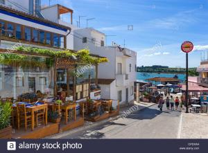 una calle en una ciudad con restaurantes y un puerto en Alvor Navy Apartment, en Alvor