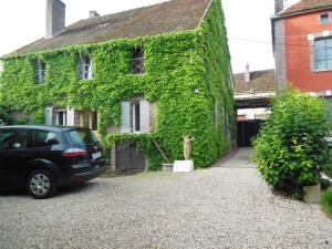 een auto geparkeerd voor een huis bedekt met klimop bij Les Bains Bed & Breakfast in Cheny