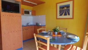 une cuisine avec une table bleue et une cuisine aux murs jaunes dans l'établissement VVF Sud Vercors, à Die