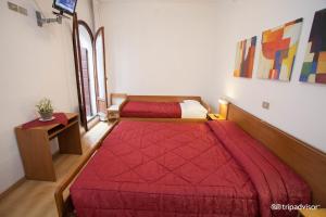 um quarto com duas camas num quarto com um cobertor vermelho em Hotel Caprera em Veneza