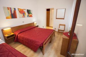 um quarto com uma cama vermelha e uma cadeira em Hotel Caprera em Veneza