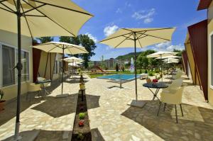 a patio with tables and umbrellas and a pool at Di Mare Holiday Village in Kranevo