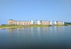 una gran masa de agua con edificios en el fondo en Coastal Apartments - Wales, en Swansea