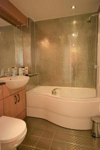 a bathroom with a tub and a sink and a toilet at Coastal Apartments - Wales in Swansea