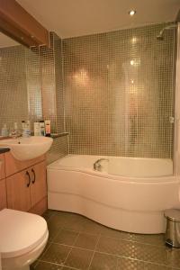 a bathroom with a tub and a sink and a toilet at Coastal Apartments - Wales in Swansea +20 photos
