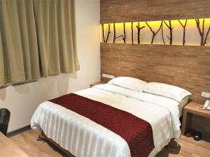 a bedroom with a large bed with a wooden headboard at Dahshin Hotel in Taipei