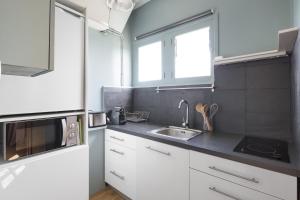 a kitchen with white cabinets and a sink at Le Gatsby by Cocoonr in Nantes